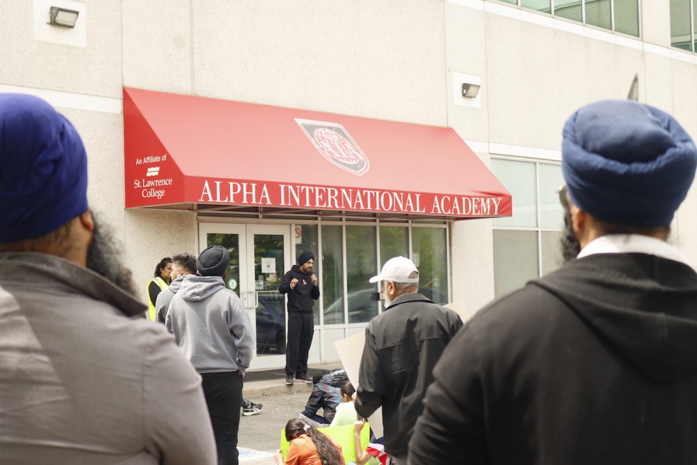 A photo of Jaspreet standing under a red awning that reads